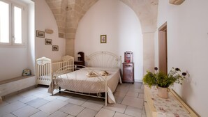 Une chambre à coucher avec un lit, un banc, une commode, un miroir et une plante en pot.