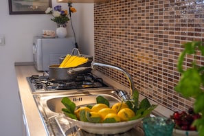 A kitchen with a stove, sink, and a bowl of lemons.