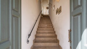 Un escalier menant à une porte dotée d’une main courante, des tableaux encadrés accrochés aux murs et un plafond en arc de cercle.