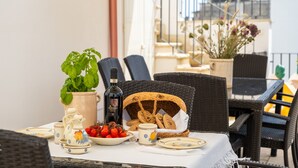 Une table à manger avec une plante en pot, une bouteille et un panier de pain.