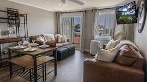 A living room with a sofa, a dining table set with plates and glasses, a ceiling fan, and a TV mounted on the wall. - ML 331: Your 1BR, bike-in/bike-out & renovated summer oasis awaits you! (Snowshoe)