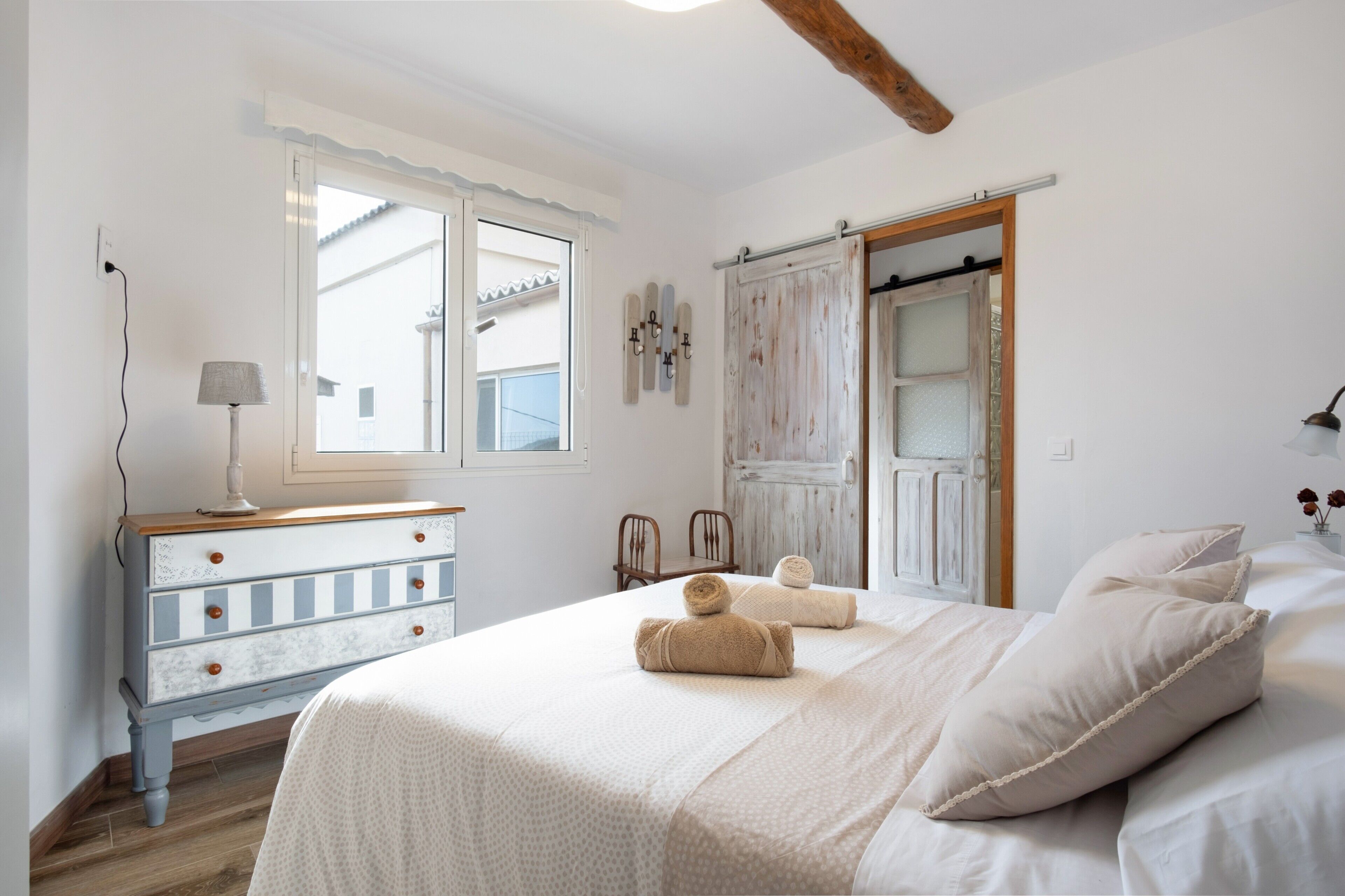A bedroom with a bed, a dresser, a lamp, and a window.