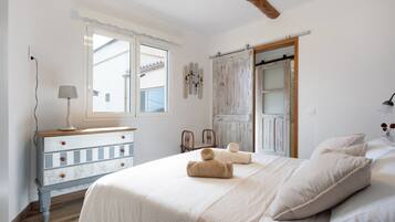 A bedroom with a bed, a dresser, a lamp, and a window.