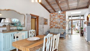 A dining area with a wooden table and white chairs, a light blue cabinet, and a tiled floor. - Holiday Home 'Las Golondrinas - B' with Sea View, Private Terrace and Wi-Fi (Jedey)