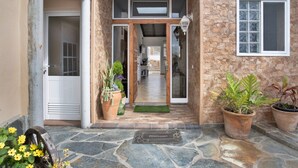 A stone-walled entrance with a wooden door, potted plants, and a welcome mat. - Holiday Home 'Las Golondrinas - B' with Sea View, Private Terrace and Wi-Fi (Jedey)