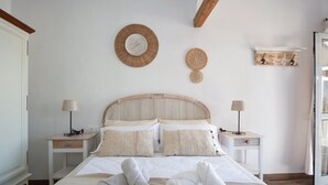 A neatly made bed with two pillows, a bedside table with a lamp, and a wall-mounted shelf with hooks. - Holiday Home 'Las Golondrinas - B' with Sea View, Private Terrace and Wi-Fi (Jedey)