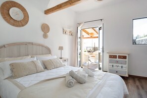 Ein Schlafzimmer mit einem Bett, einem Schminktisch, einem Fenster und einer Tür, die auf einen Balkon führt.