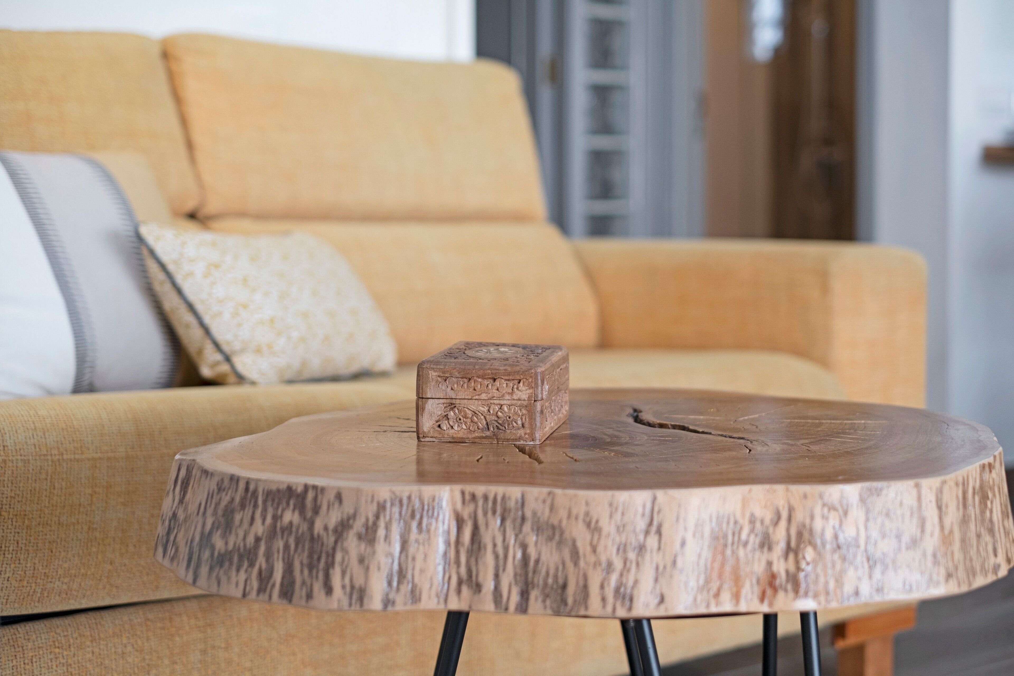Ein runder Holztisch mit einer Ablage, eine Couch mit Kissen und ein Holzschrank im Hintergrund.