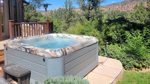 Ein Whirlpool auf einer Holzterrasse mit Blick auf eine Berglandschaft.