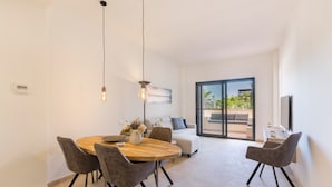A modern dining area with a round wooden table, grey upholstered chairs, and pendant lighting.