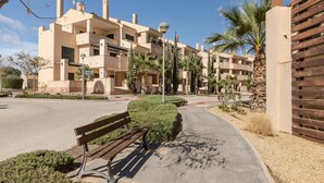 A residential building with multiple balconies, a paved walkway, and a bench.