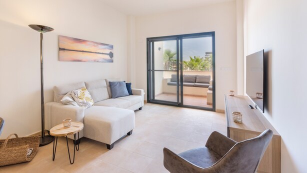 A modern living room with a sofa, a coffee table, a floor lamp, and a TV.