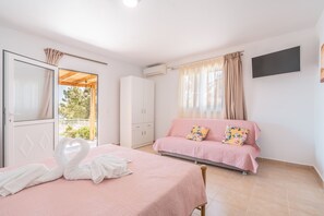Un dormitorio con cama, sofá, armario, aire acondicionado y televisor.