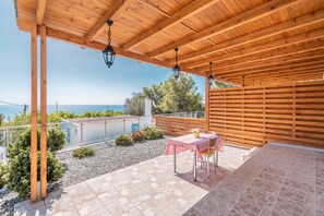 A covered patio with a table and chairs, a view of the sea, and a wooden fence. - Studio Apartment 'Solymar Prive  Sea View 2' with Sea View, Wi-Fi and Air Conditioning (Archangelos)