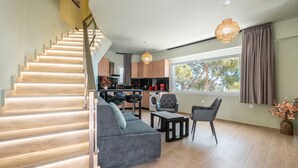 A modern interior with a staircase, grey sofa, black chairs, a kitchen, and a large window. - Apartment 'Solymar Prive  Sea View' with Sea View, Wi-Fi and Air Conditioning (Archangelos)