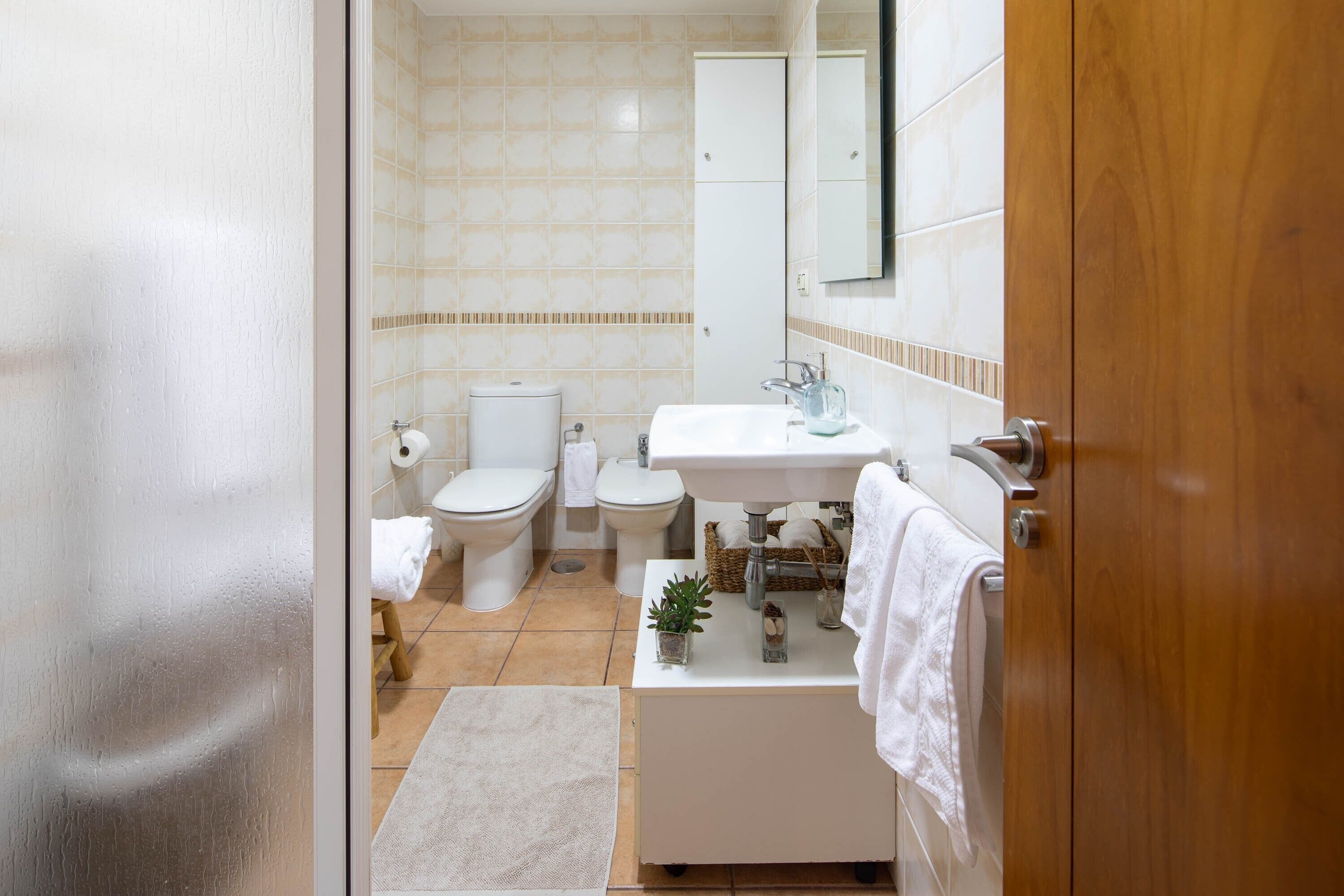 Un baño con inodoro, bidé, lavabo y espejo.