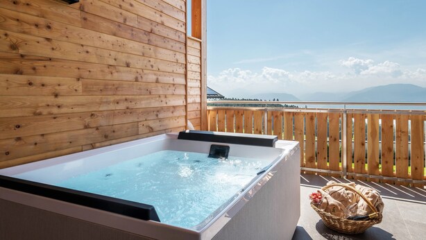 A wooden cabin with a hot tub and a wooden deck overlooking a mountainous landscape. - Apartment 'Zirm' with Mountain View, Private Terrace and Wi-Fi (Jenesien)