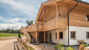 A wooden cabin with a balcony, a staircase, and a dirt path leading to the entrance. - Apartment 'Zirm' with Mountain View, Private Terrace and Wi-Fi (Jenesien)