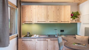 A modern kitchen with wooden cabinets, a sink, and a dining area with a round table and chairs. - Apartment 'Zirm' with Mountain View, Private Terrace and Wi-Fi (Jenesien)