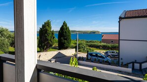 A balcony with a view of a coastal area, including a body of water and distant hills. - 2 bedroom beach front apartment in Rtina (Rtina)
