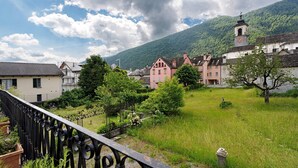 A town with traditional architecture, a prominent clock tower, and a lush green landscape. - Apartment 'Casa Anna' with Mountain View and Private Terrace (Santa Maria Maggiore)