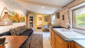 Una cocina acogedora con armarios de madera, un ventanal grande y una zona de comedor con mesa y sofá.