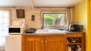 Una cocina con armarios de madera, microondas, tostadora, fregadero y ventana con vista a zonas verdes.