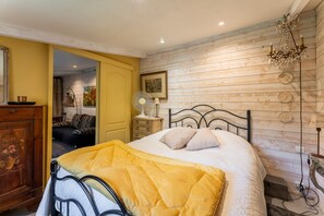 Una camera da letto con un letto, pannelli di legno alle pareti, un lampadario, un comodino e uno specchio.