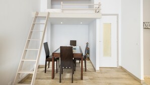 Una habitación con una cama litera, una mesa de comedor con sillas y una escalera.