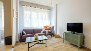 Un salón con sofá, mesa de centro, televisor y un escritorio con silla.