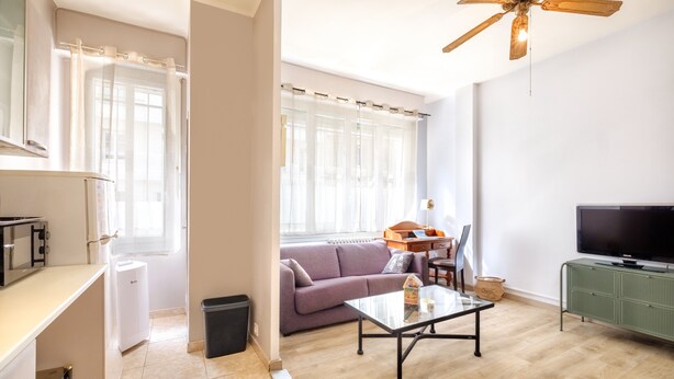Una sala de estar con sofá, mesa de centro, televisor y ventilador de techo.