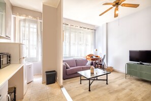 Un salon comprenant un canapé, une table basse, un téléviseur et un ventilateur de plafond.