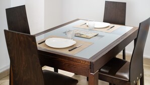 Una mesa de comedor con cuatro sillas, un mantel individual, un vaso, un plato y una servilleta.