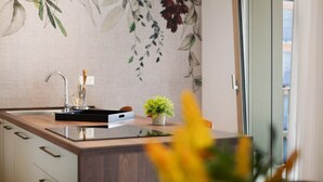 Une cuisine au design moderne, comprenant un évier, une petite plante en pot et un mur décoratif orné de motifs de feuilles.
