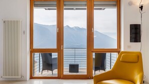 Une pièce dotée d’une grande porte-fenêtre coulissante donnant sur un balcon avec vue sur les montagnes.