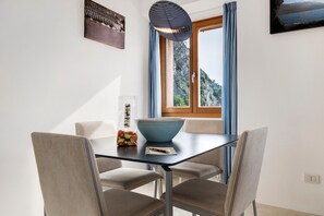 Un comedor con una mesa, sillas, un cuenco y una ventana con cortinas.