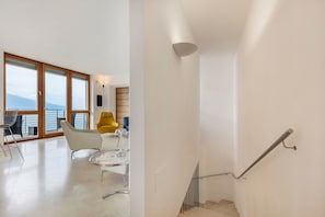 A modern interior with a staircase, a balcony with a view, and contemporary furniture.