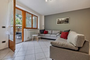 A living room with a sofa, a small table, a radiator, and a window with curtains.