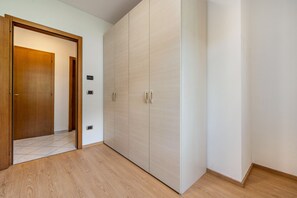 A room with a wooden wardrobe, a door, and a tiled floor.