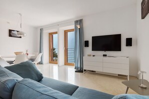 A modern living room with a sofa, TV, and dining area.