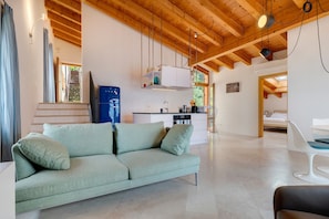 A modern living room with a sofa, a dining area, and a kitchen.