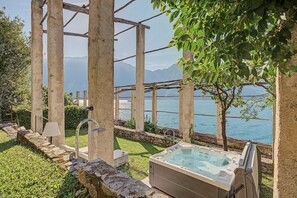 A hot tub with a stone wall and a view of a lake. - Apartment 'Antea' with Lake View, Wi-Fi and Air Conditioning (Limone sul Garda)