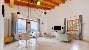 Sala de estar moderna com área de jantar, sofá, televisão e vista para as montanhas.