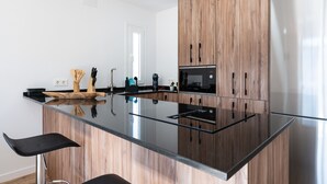 A modern kitchen with a wooden cabinet, a black countertop, and a stainless steel refrigerator. - Casa Emilio Apartment with Wi-Fi and Air Conditioning (Benalmádena)