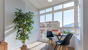 A room with a large window, a potted plant, two chairs, a small table, and a wooden cabinet. - Casa Emilio Apartment with Wi-Fi and Air Conditioning (Benalmádena)