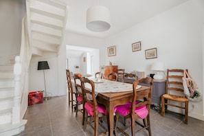 A dining area with a wooden table, chairs, and a staircase.