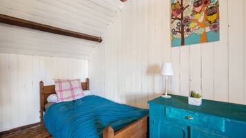 Quarto com cama de madeira, cómoda azul-turquesa e um quadro na parede com corujas e flores.