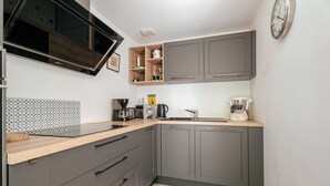 A modern kitchen with grey cabinets, a wooden countertop, a built-in microwave, and a tiled backsplash. - Holiday Home 'Maison Pleneuf Val André Proche Mer' with Private Terrace, Private Garden and Wi-Fi (Pléneuf-Val-André)