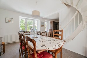 A dining area with a table, chairs, and a staircase. - Holiday Home 'Maison Pleneuf Val André Proche Mer' with Private Terrace, Private Garden and Wi-Fi (Pléneuf-Val-André)
