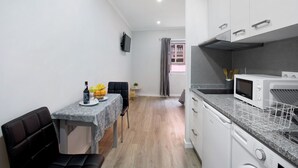 Una cucina compatta con forno a microonde, lavastoviglie e zona pranzo con tavolo e sedie.